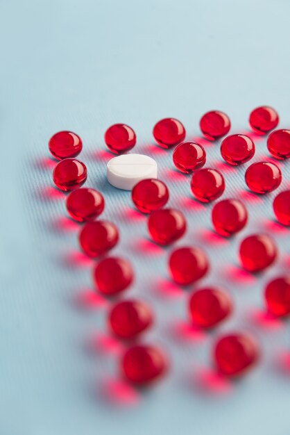 Una tableta redonda blanca en una cuadrícula de cápsulas rojas