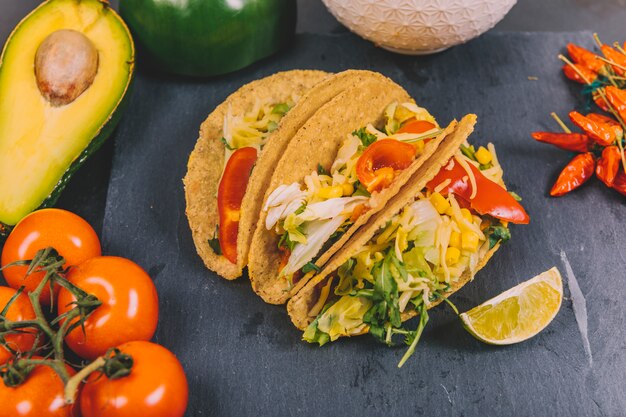 Tacos de carne mexicana con verduras; tomate; aguacate en pizarra negra