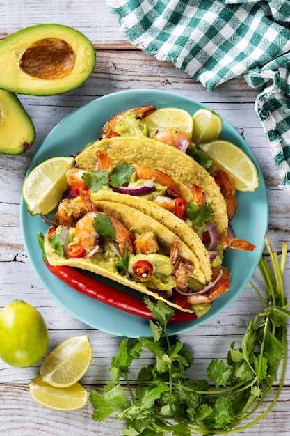 Tacos mexicanos con camarones, guacamole y verduras en mesa de madera