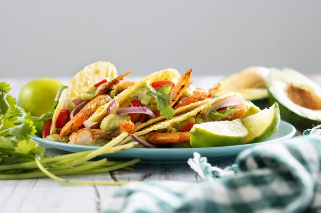 Tacos mexicanos con camarones, guacamole y verduras en mesa de madera