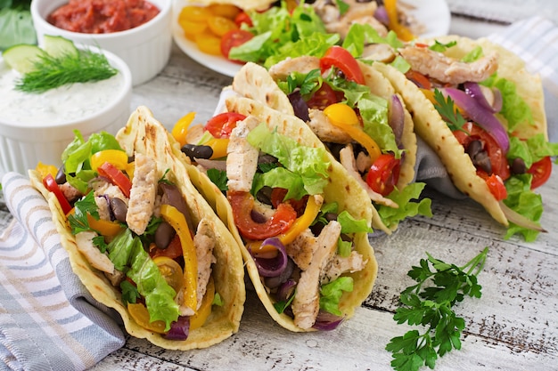 Tacos mexicanos con pollo, pimientos, frijoles negros y vegetales frescos.