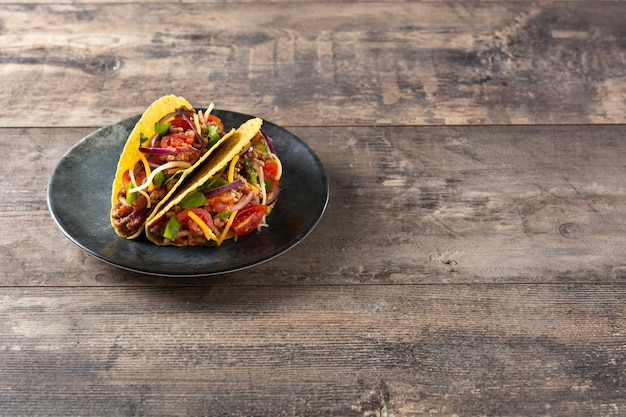 Tacos mexicanos tradicionales con carne y verduras en la mesa de madera