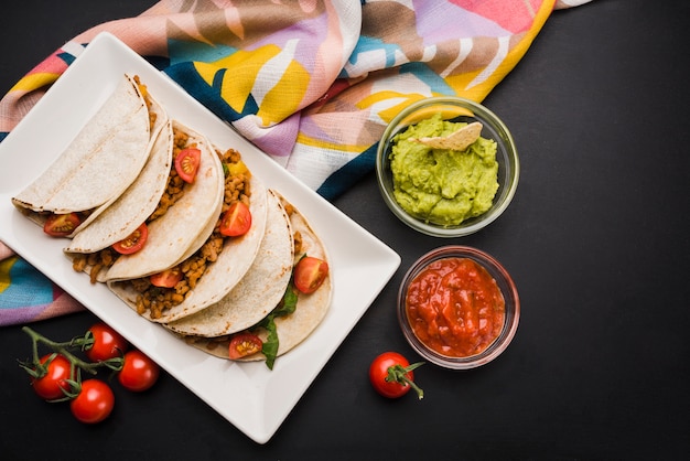 Tacos en un plato cerca de la servilleta y salsas