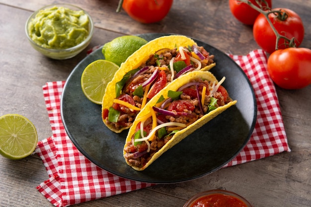 Tacos tradicionales mexicanos con carne y verduras en la mesa de madera