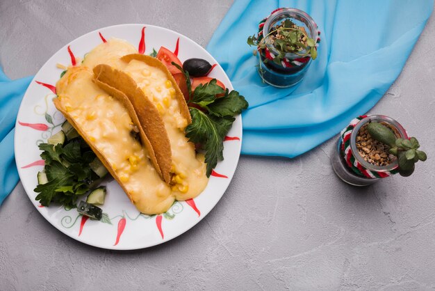 Tacos entre las verduras en el plato cerca de las plantas de interior y la servilleta