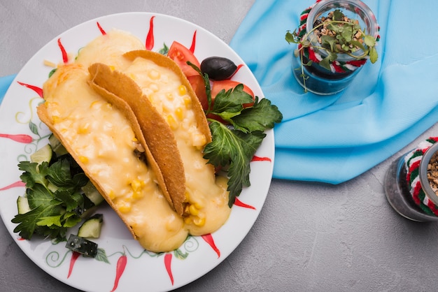 Foto gratuita tacos entre verduras en un plato cerca de las plantas y la servilleta