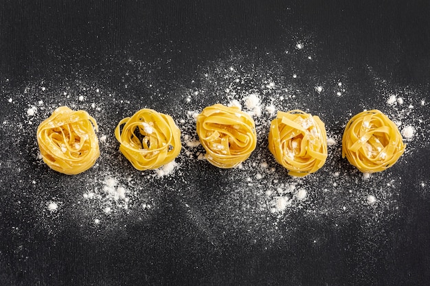 Tagliatelle crudo con harina sobre fondo negro