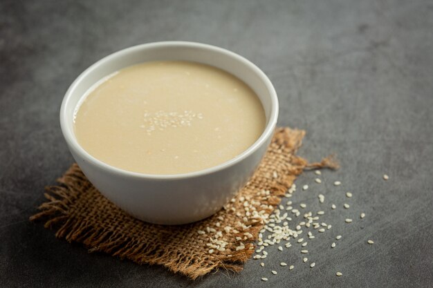 Tahini y semillas de sésamo sobre fondo oscuro