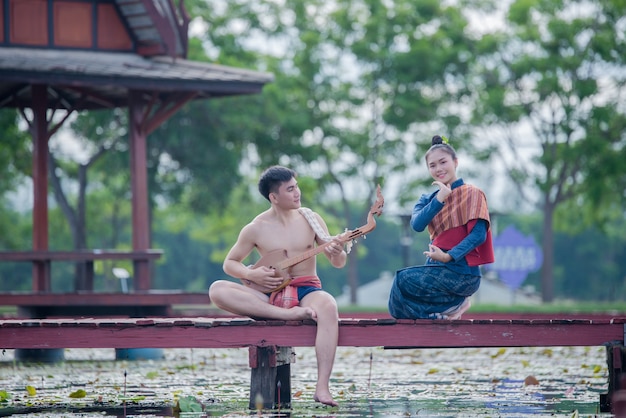 Tailandia mujeres y hombres en traje nacional con pin de guitarra (instrumento de cuerda pinchada)