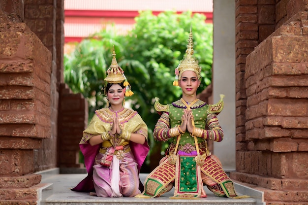 Foto gratuita tailandia pareja de baile en representaciones de khon enmascarado con templo antiguo