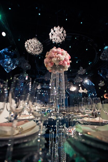 Tall centro de flores rosadas y cadenas de cristal se encuentra en la mesa de la cena