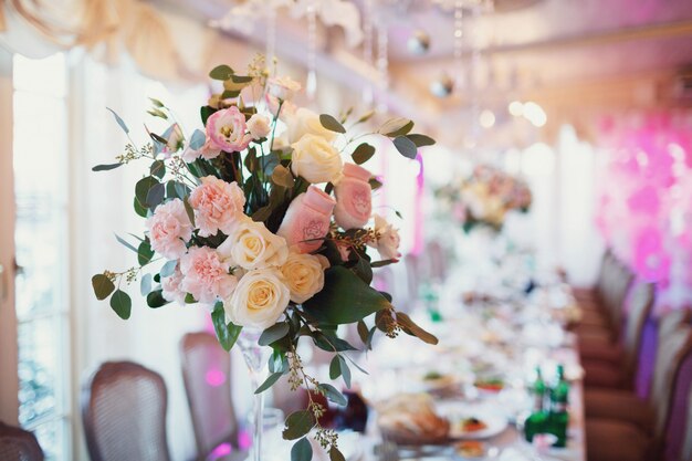 Tall vasos con flores de color rosa de pie en la mesa de cena largo
