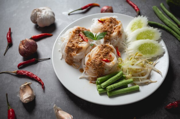Tallarines de arroz tailandeses en salsa de curry de los pescados en la tabla de madera.