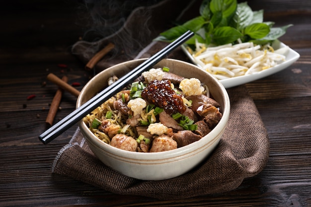 Foto gratuita tallarines con carne de cerdo y albóndigas, pasta de chile con sopa estilo tailandés y verdura. fideos de barco. enfoque selectivo