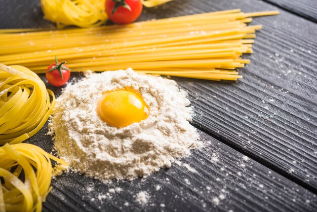 Tallarines y espaguetis con yema de huevo en harina sobre la mesa de madera