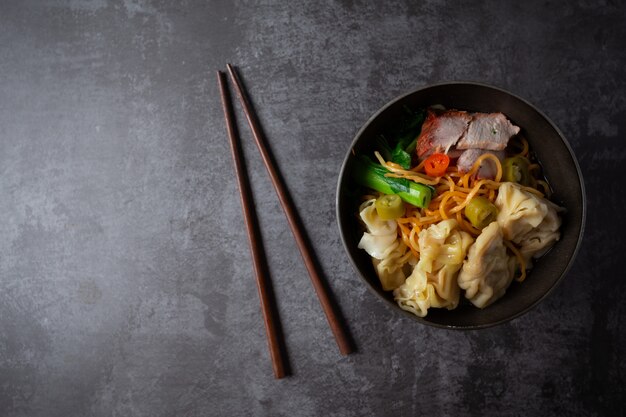 Tallarines de huevo con cerdo y wonton asados rojos en la tabla.