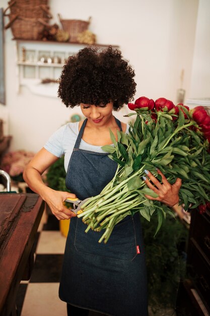 Foto gratuita tallo de corte florista femenino de flores rojas en la tienda