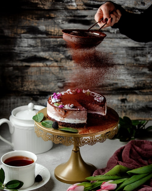 Tamiz de café en polvo sobre pastel de cacao con crema de vainilla y café