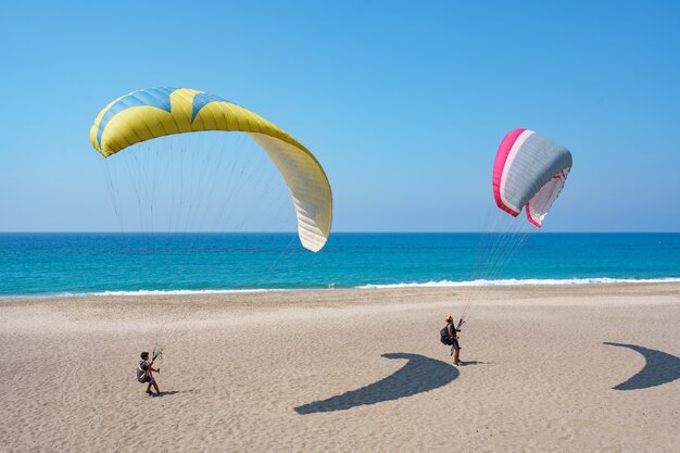 Tándem de parapente volando sobre la orilla del mar con agua azul y cielo en horison. Vista del parapente y la laguna azul en Turquía.