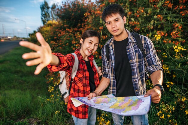 Tanto turistas masculinos como femeninos llevan una mochila de pie en un jardín de flores.