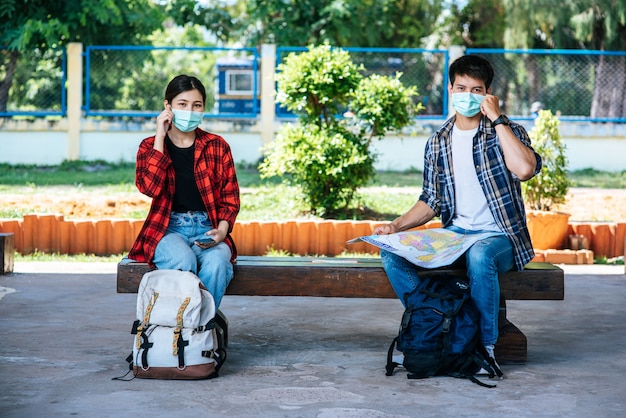 Tanto turistas masculinos como femeninos se sientan y miran el mapa al lado del ferrocarril.