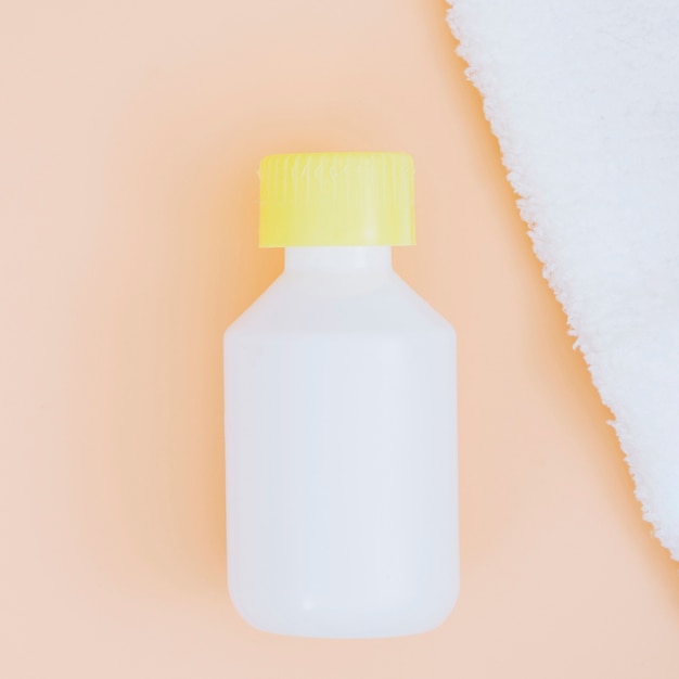 Tapa de botella amarilla cerrada con servilleta blanca sobre fondo beige