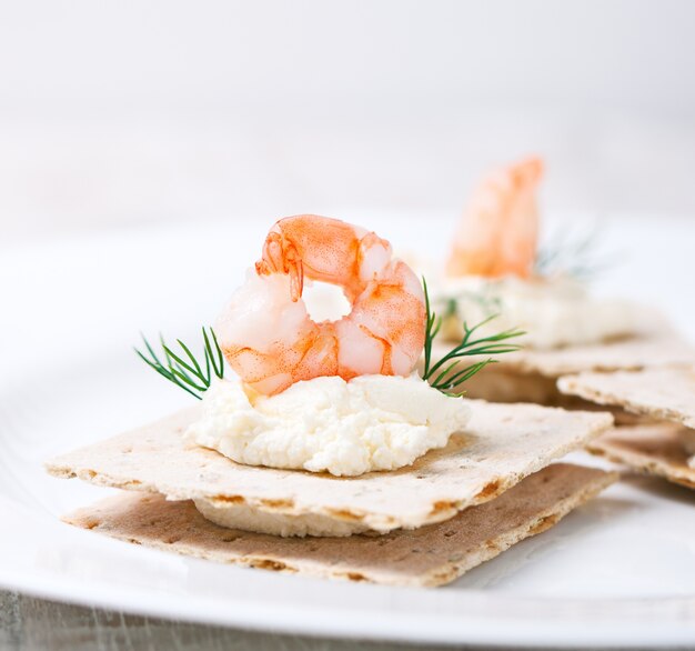 Tapa de gambas con queso debajo en un plato