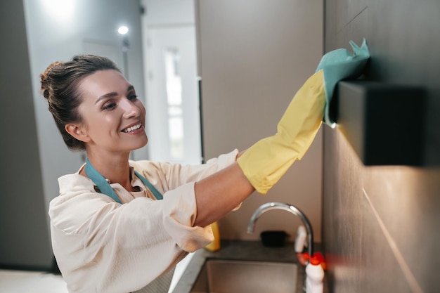 Tareas. Mujer morena joven que limpia las superficies en la cocina