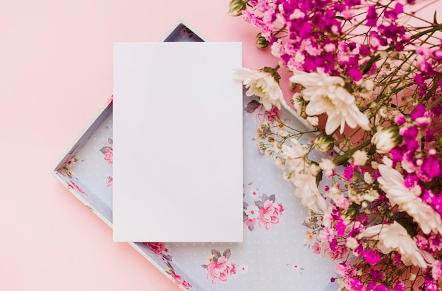 Tarjeta blanca en blanco y ramo de flores con una caja vacía sobre fondo rosa