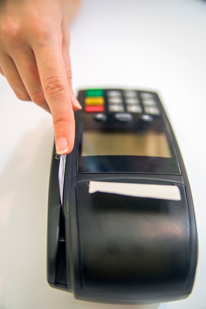 Tarjeta De Crédito En La Tienda. Manos femeninas con tarjeta de crédito y terminal de banco. Imagen en color de un POS y tarjetas de crédito.