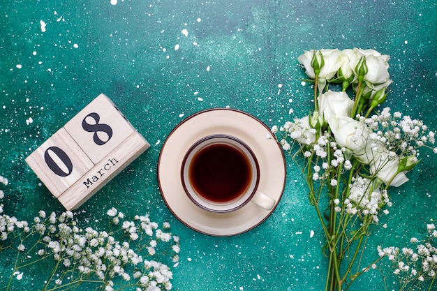 Tarjeta del día de la mujer del 8 de marzo con flores blancas, dulces y una taza de té