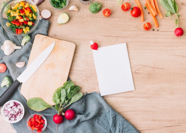 Tarjeta de felicitación en blanco con verduras frescas para ensalada en mesa de madera