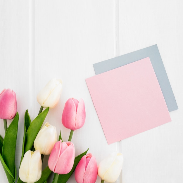 Tarjeta de felicitación y tulipanes en el fondo de madera blanco para el día de madre