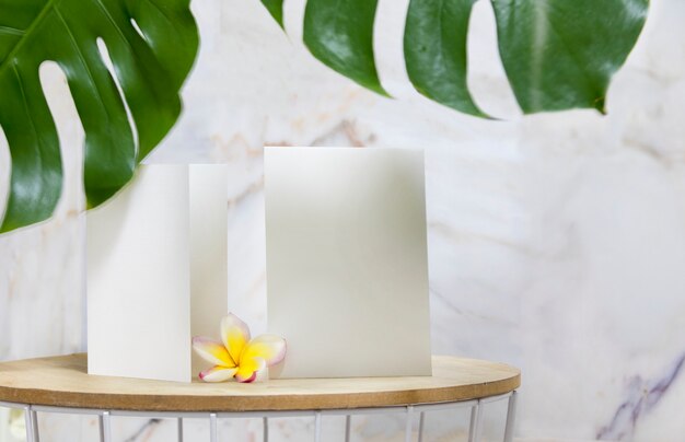 Tarjeta de invitación blanca y flor de plumeria en flor.