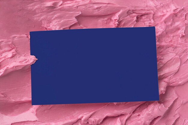 Tarjeta de visita azul sobre textura de glaseado rosa