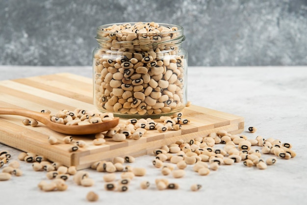 Foto gratuita tarro de cristal de frijoles blancos sobre plancha de madera.