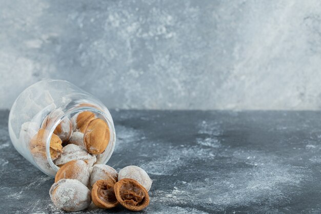 Un tarro de cristal lleno de galletas dulces con forma de nuez.