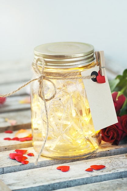 Tarro de cristal con luces encendidas y una carta atada con una cuerda