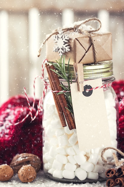 Tarro con malvavisco y pequeño regalo con decoraciones de Navidad,