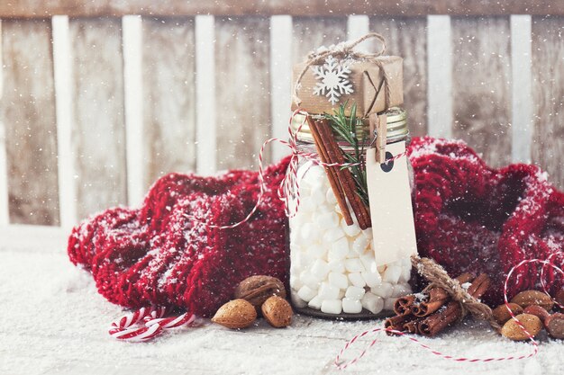 Tarro con malvavisco y pequeño regalo con decoraciones de Navidad,