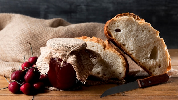 Foto gratuita tarro de mermelada de cerezas con rebanadas de pan