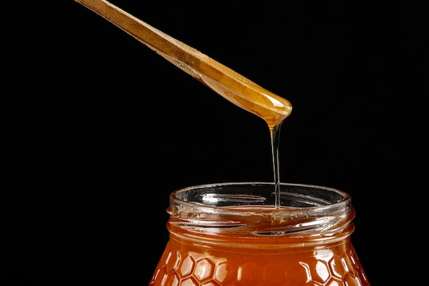 Foto gratuita tarro de miel con cuchara de madera