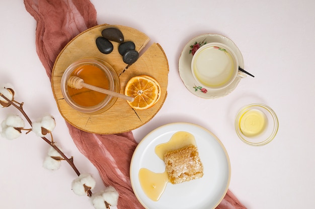 Tarro de miel; rodajas de cítricos secos; los últimos; panal de miel y rama de algodón sobre fondo blanco