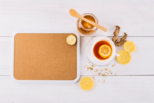 Tarro de miel y té de limón cerca de jengibre sobre fondo de madera