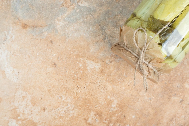 Foto gratuito un tarro de pepinos encurtidos caseros sobre superficie de mármol