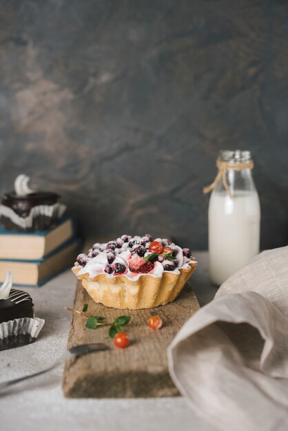 Tarta de bayas en tablero de madera con botella de leche