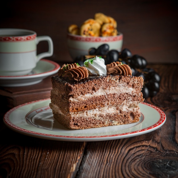 Tarta casera de primer plano con una taza de té, galletas y bayas en la mesa de madera