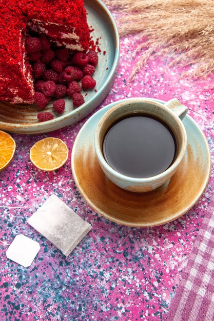 Tarta de frambuesa roja de media vista superior con taza de té en el escritorio rosa.