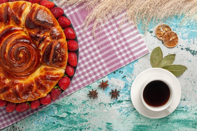 Tarta de fresa vista superior con taza de té en la superficie azul