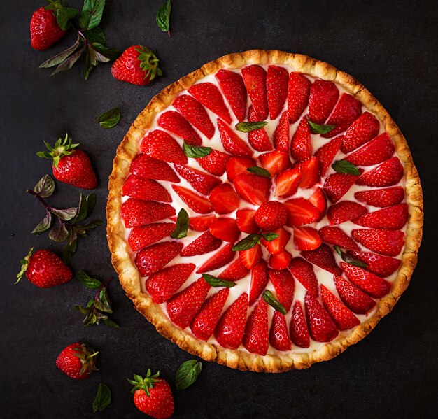 Tarta de fresas y crema batida decorada con hojas de menta. Vista superior